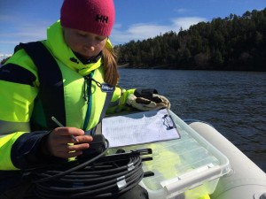 En miljöprovtagare skriver anteckningar om vattenprovtagning ute på båt.